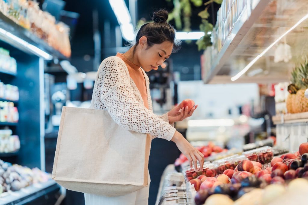 a woman at the grocery store holding an apple