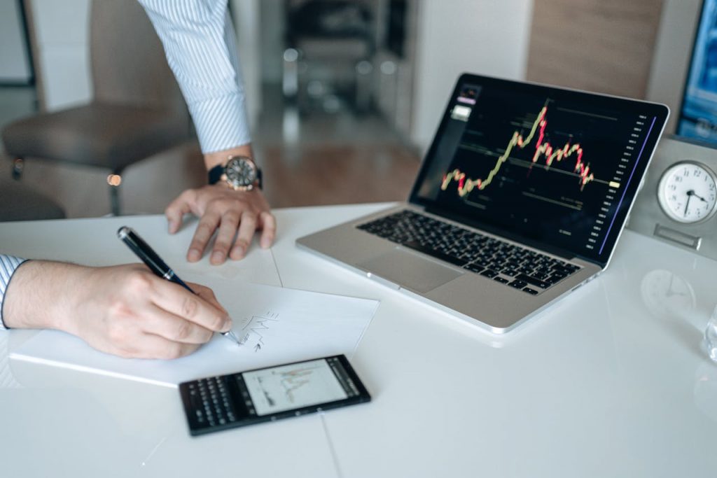 A person writing notes with reference to investment market movements