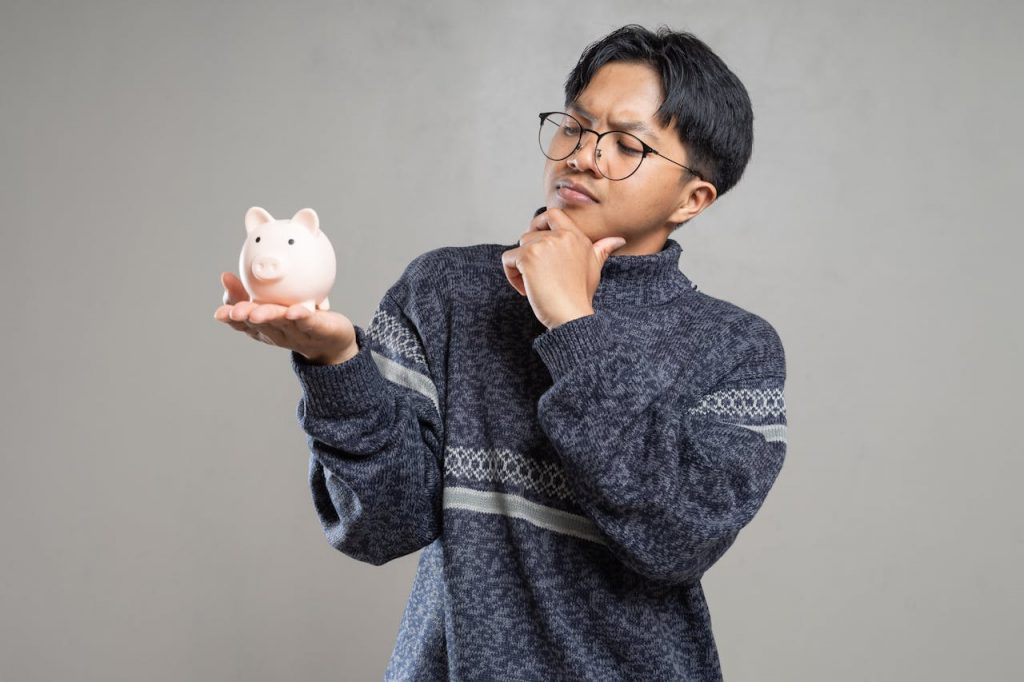 a man wearing glasses holding up a piggy bank