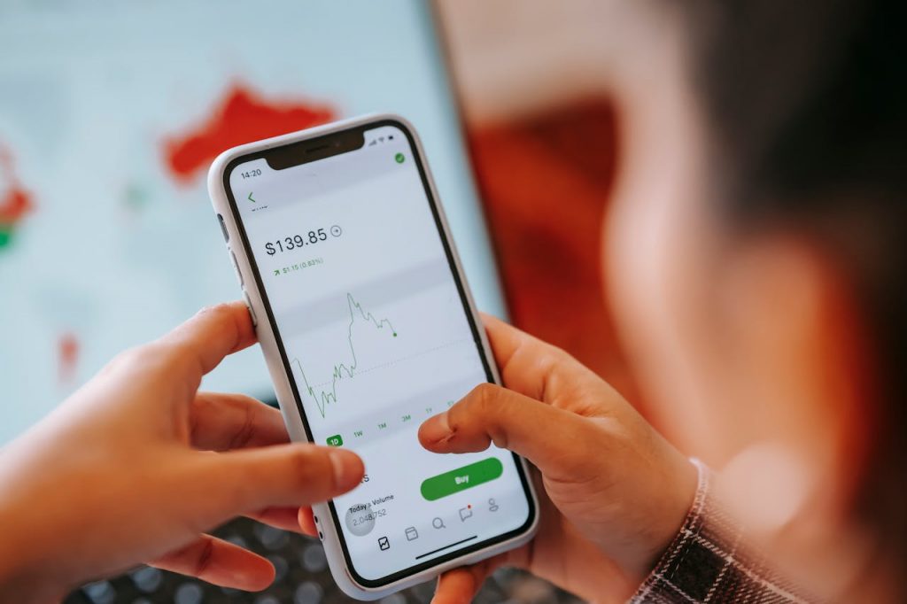 Hands using smartphone app to track and analyze stock market trends