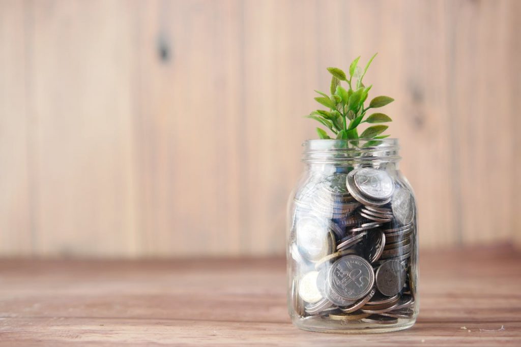 A jar filled with coins and a plant symbolizes growth in savings and investment
