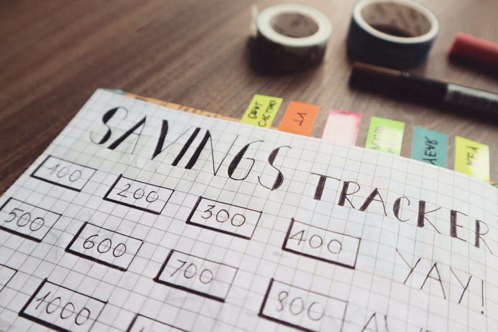 Close-up of a handmade savings tracker with colored tabs on a wooden table, ideal for financial planning visuals